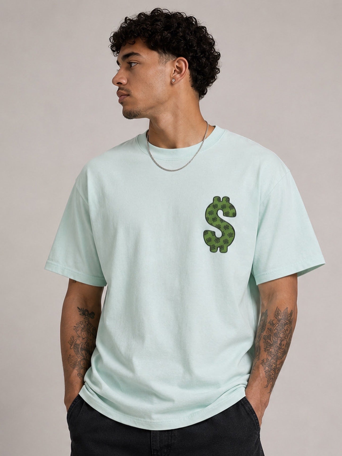 Person wearing a light blue t-shirt with a green dollar sign design on a beige background
