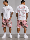Man wearing 'Anti Broke Girls Club' t-shirt and shorts with pink and brown camouflage pattern.
